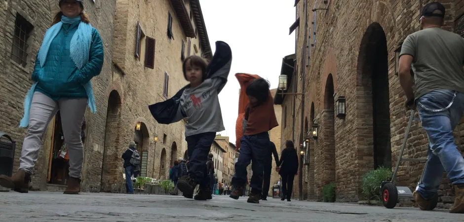 Two kids running down an old Italian street pretending to be aeroplanes